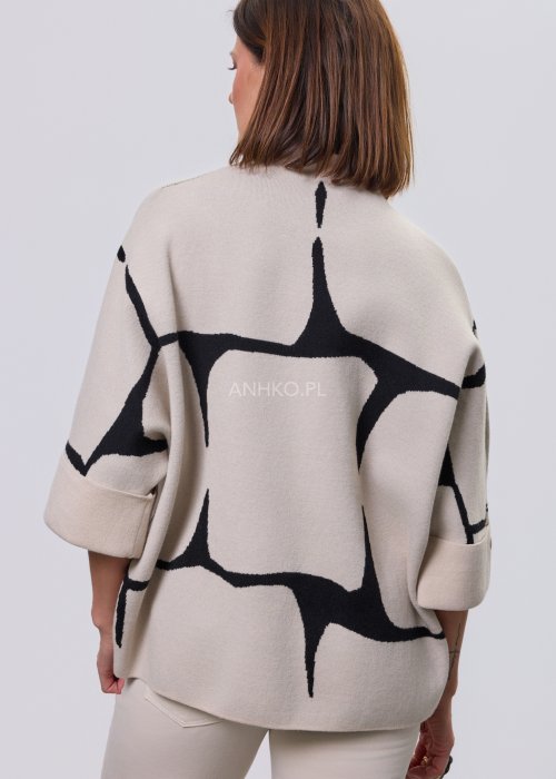 Ecru damski sweter o luźnym kroju z półgolfem i rękawami 3/4, zdobiony kontrastowym białym, abstrakcyjnym wzorem, prezentowany na modelce na jasnym tle