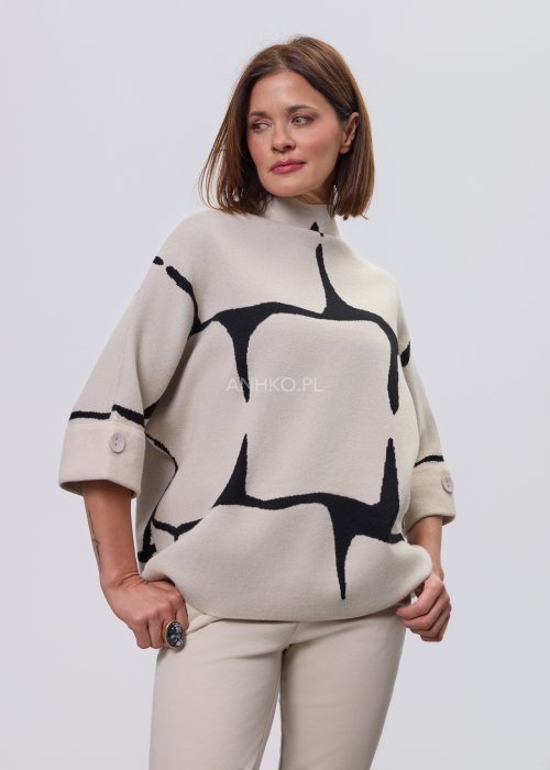 Ecru damski sweter o luźnym kroju z półgolfem i rękawami 3/4, zdobiony kontrastowym białym, abstrakcyjnym wzorem, prezentowany na modelce na jasnym tle