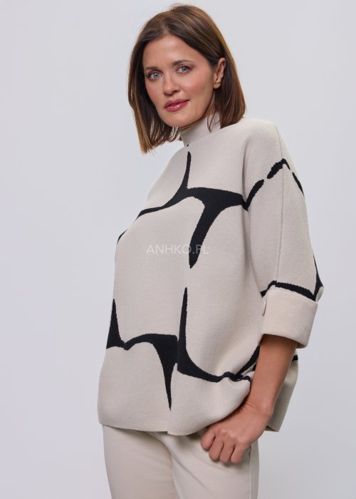 Ecru damski sweter o luźnym kroju z półgolfem i rękawami 3/4, zdobiony kontrastowym białym, abstrakcyjnym wzorem, prezentowany na modelce na jasnym tle