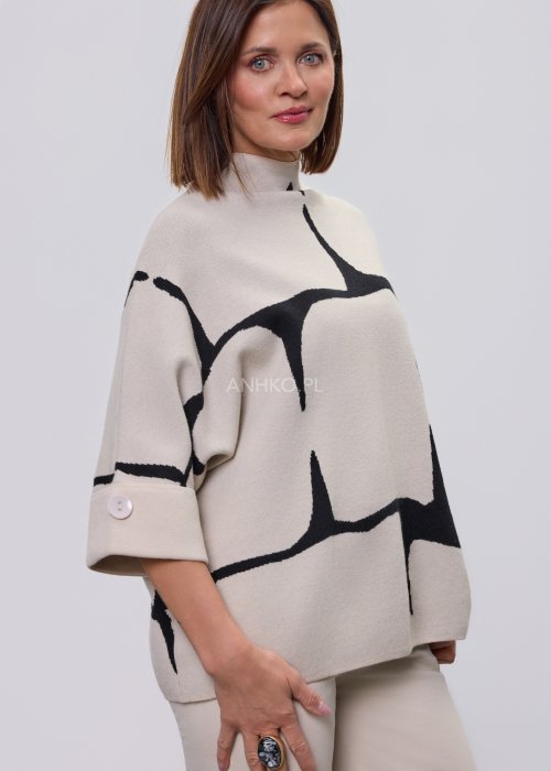 Ecru damski sweter o luźnym kroju z półgolfem i rękawami 3/4, zdobiony kontrastowym białym, abstrakcyjnym wzorem, prezentowany na modelce na jasnym tle