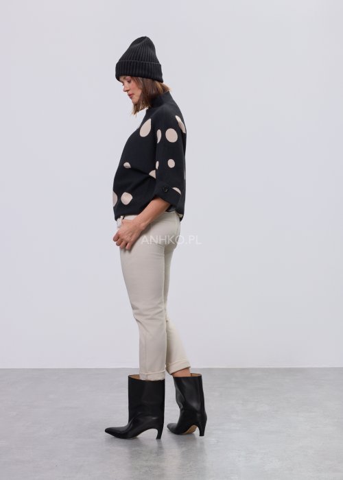 Czarny damski sweter o luźnym kroju z półgolfem i rękawami 3/4, ozdobiony kontrastowym wzorem beżowych kropek, prezentowany na modelce na jasnym tle