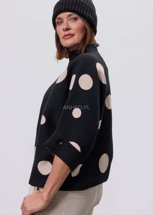 Czarny damski sweter o luźnym kroju z półgolfem i rękawami 3/4, ozdobiony kontrastowym wzorem beżowych kropek, prezentowany na modelce na jasnym tle