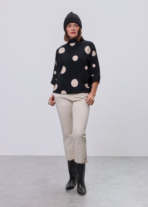 Czarny damski sweter o luźnym kroju z półgolfem i rękawami 3/4, ozdobiony kontrastowym wzorem beżowych kropek, prezentowany na modelce na jasnym tle