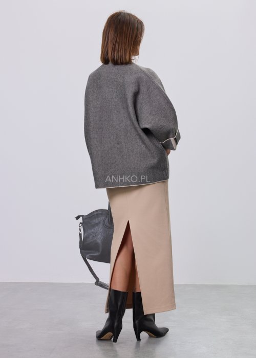 Damska, luźna bluzka o kroju oversize w kolorze szarym, z półgolfem i rękawami 3/4, ozdobiona pionowym kontrastowym paskiem, prezentowana na modelce na jasnym tle