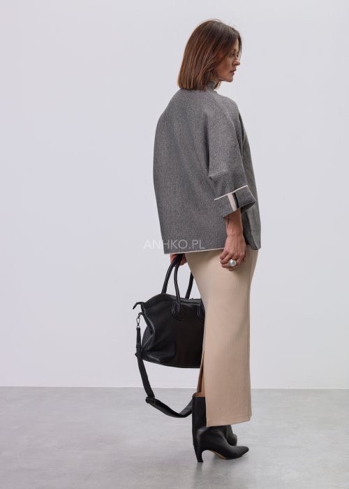 Damska, luźna bluzka o kroju oversize w kolorze szarym, z półgolfem i rękawami 3/4, ozdobiona pionowym kontrastowym paskiem, prezentowana na modelce na jasnym tle