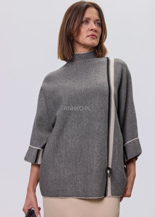 Damska, luźna bluzka o kroju oversize w kolorze szarym, z półgolfem i rękawami 3/4, ozdobiona pionowym kontrastowym paskiem, prezentowana na modelce na jasnym tle