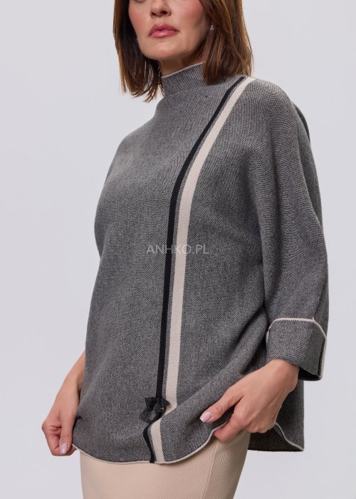 Damska, luźna bluzka o kroju oversize w kolorze szarym, z półgolfem i rękawami 3/4, ozdobiona pionowym kontrastowym paskiem, prezentowana na modelce na jasnym tle