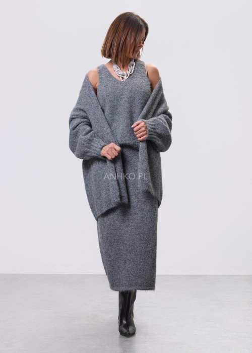 Trzyczęściowy komplet w odcieniu szarości: dzianinowa sukienka midi bez rękawów, długi luźny kardigan oraz dopasowany top, całość uzupełniona masywnym srebrnym naszyjnikiem i czarnymi botkami.