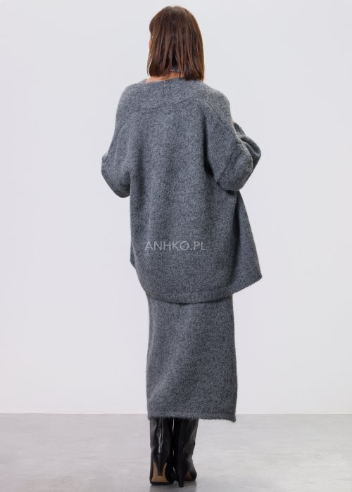 Trzyczęściowy komplet w odcieniu szarości: dzianinowa sukienka midi bez rękawów, długi luźny kardigan oraz dopasowany top, całość uzupełniona masywnym srebrnym naszyjnikiem i czarnymi botkami.