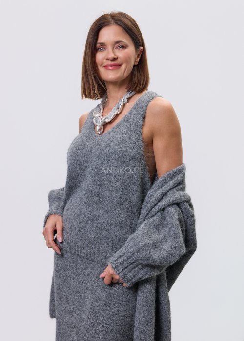 Trzyczęściowy komplet w odcieniu szarości: dzianinowa sukienka midi bez rękawów, długi luźny kardigan oraz dopasowany top, całość uzupełniona masywnym srebrnym naszyjnikiem i czarnymi botkami.
