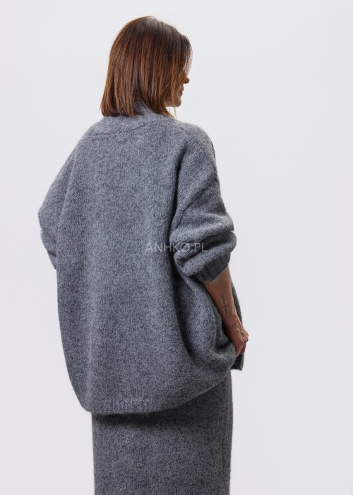 Trzyczęściowy komplet w odcieniu szarości: dzianinowa sukienka midi bez rękawów, długi luźny kardigan oraz dopasowany top, całość uzupełniona masywnym srebrnym naszyjnikiem i czarnymi botkami.