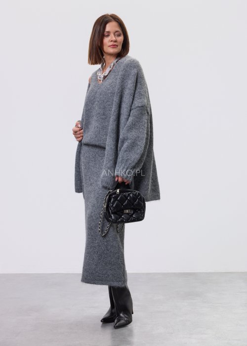 Trzyczęściowy komplet w odcieniu szarości: dzianinowa sukienka midi bez rękawów, długi luźny kardigan oraz dopasowany top, całość uzupełniona masywnym srebrnym naszyjnikiem i czarnymi botkami.