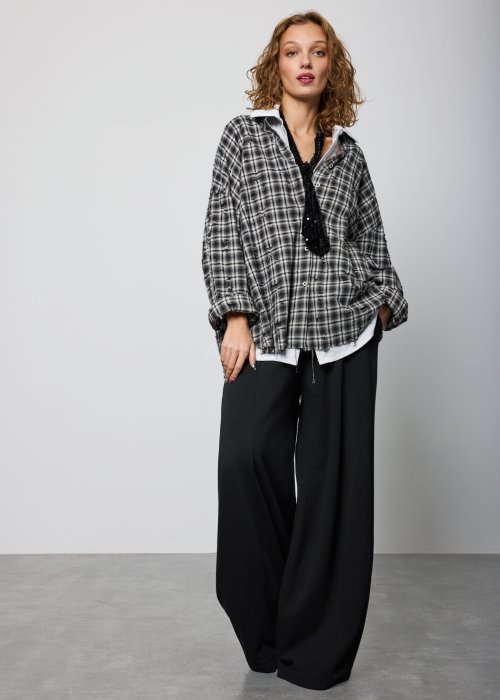 Szara koszula damska oversize w kratę z artystycznymi przetarciami i klasycznym kołnierzykiem. Bawełniany model w stylu grunge prezentowany w miejskiej stylizacji.