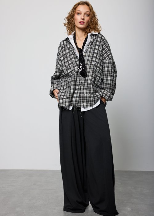 Szara koszula damska oversize w kratę z artystycznymi przetarciami i klasycznym kołnierzykiem. Bawełniany model w stylu grunge prezentowany w miejskiej stylizacji.