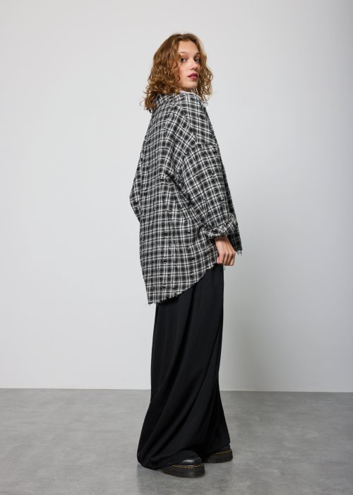 Szara koszula damska oversize w kratę z artystycznymi przetarciami i klasycznym kołnierzykiem. Bawełniany model w stylu grunge prezentowany w miejskiej stylizacji.