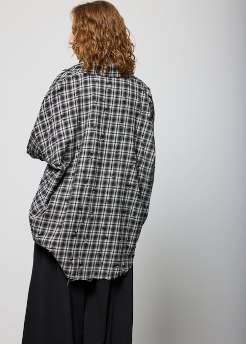 Szara koszula damska oversize w kratę z artystycznymi przetarciami i klasycznym kołnierzykiem. Bawełniany model w stylu grunge prezentowany w miejskiej stylizacji.