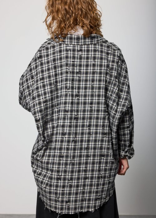 Szara koszula damska oversize w kratę z artystycznymi przetarciami i klasycznym kołnierzykiem. Bawełniany model w stylu grunge prezentowany w miejskiej stylizacji.