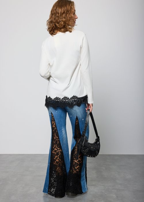 Damskie jeansy z wysokim stanem w kolorze niebieskim, dopasowane w biodrach, z rozszerzanymi nogawkami i wstawkami z czarnej koronki po bokach; widok od tyłu, jasne przetarcia