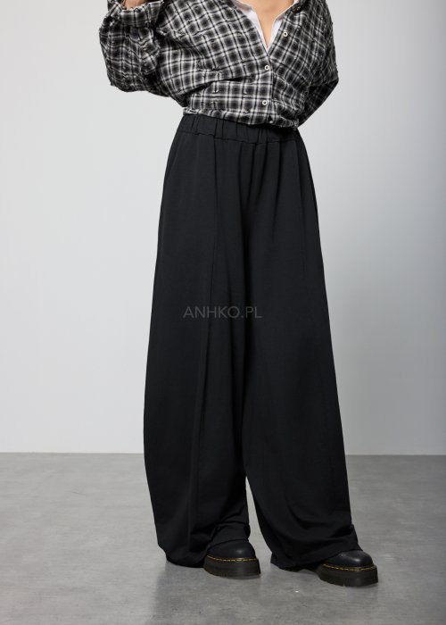 Czarne spodnie damskie o szerokich nogawkach z elastyczną talią, luźny fason w minimalistycznej stylizacji.
