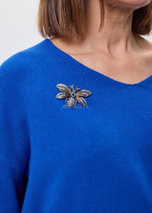 Złota broszka w kształcie pszczoły z granatowymi kryształkami przypięta do niebieskiego swetra, elegancki dodatek biżuteryjny do stylizacji damskiej