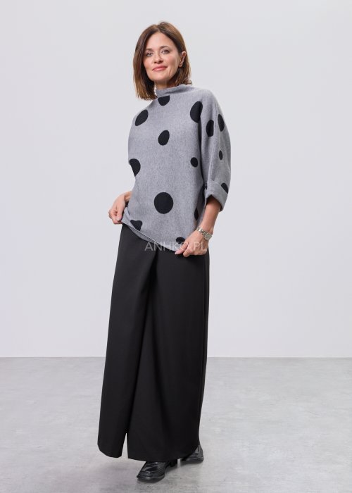 Szara damska bluzka o luźnym kroju z półgolfem, wykonana z miękkiej dzianiny, ozdobiona dużym czarnym wzorem w grochy; rękawy 3/4 z możliwością podpięcia guzikiem