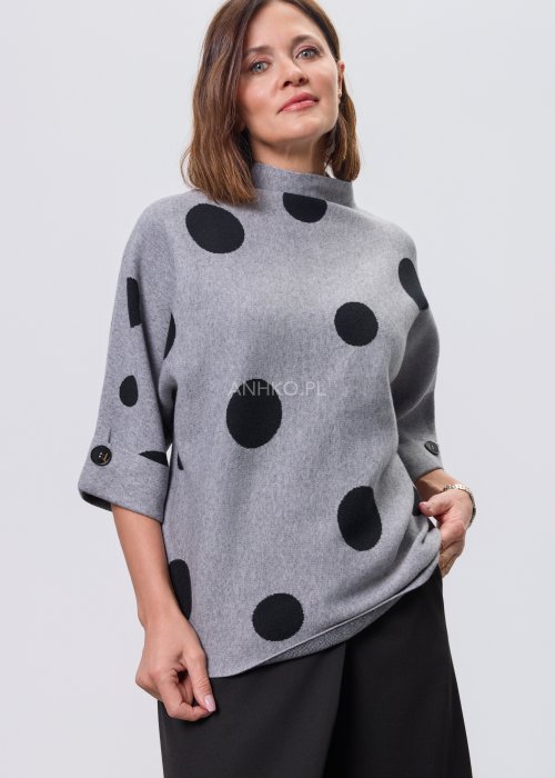Szara damska bluzka o luźnym kroju z półgolfem, wykonana z miękkiej dzianiny, ozdobiona dużym czarnym wzorem w grochy; rękawy 3/4 z możliwością podpięcia guzikiem