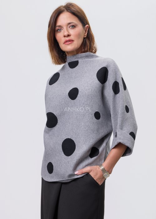 Szara damska bluzka o luźnym kroju z półgolfem, wykonana z miękkiej dzianiny, ozdobiona dużym czarnym wzorem w grochy; rękawy 3/4 z możliwością podpięcia guzikiem