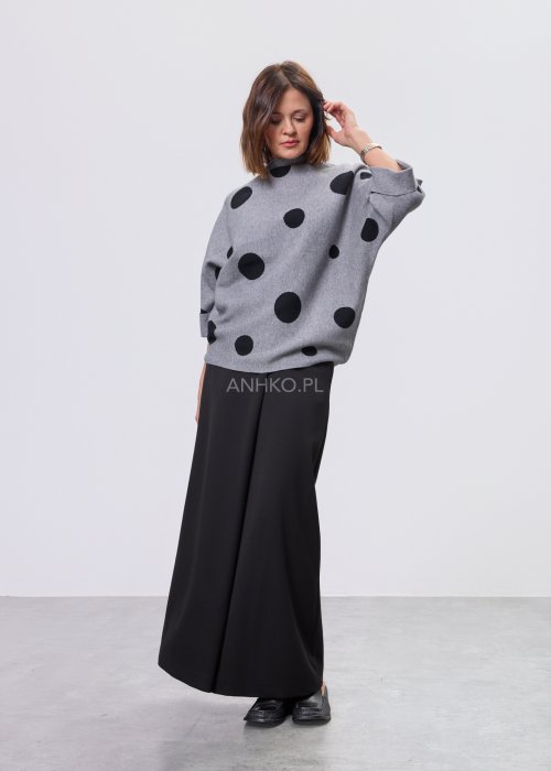 Szara damska bluzka o luźnym kroju z półgolfem, wykonana z miękkiej dzianiny, ozdobiona dużym czarnym wzorem w grochy; rękawy 3/4 z możliwością podpięcia guzikiem