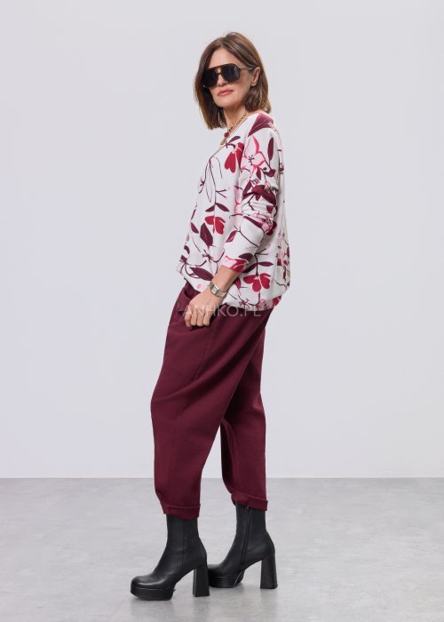 Damska bluzka z dzianiny w kwiatowy wzór w odcieniach bordo, różu i kremu; dekolt w serek, długie rękawy, luźny fason.