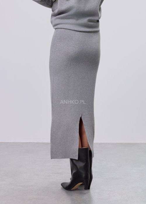 Modelka w szarym, dzianinowym komplecie dwuczęściowym: luźny sweter z długim rękawem i czarnym abstrakcyjnym nadrukiem z przodu oraz dopasowana spódnica midi w tym samym kolorze