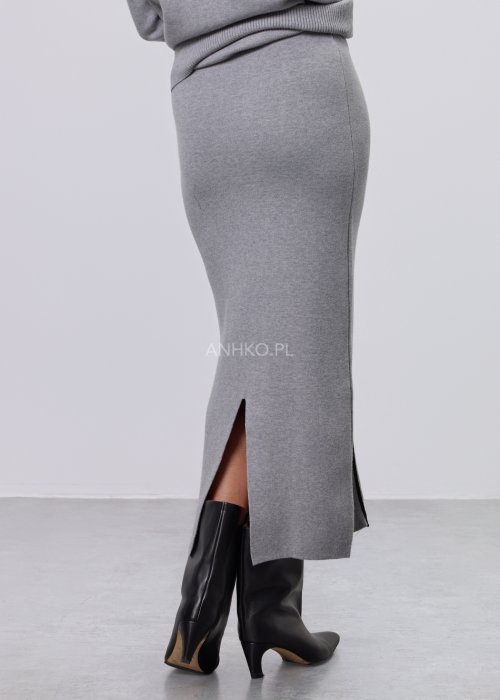 Modelka w szarym, dzianinowym komplecie dwuczęściowym: luźny sweter z długim rękawem i czarnym abstrakcyjnym nadrukiem z przodu oraz dopasowana spódnica midi w tym samym kolorze