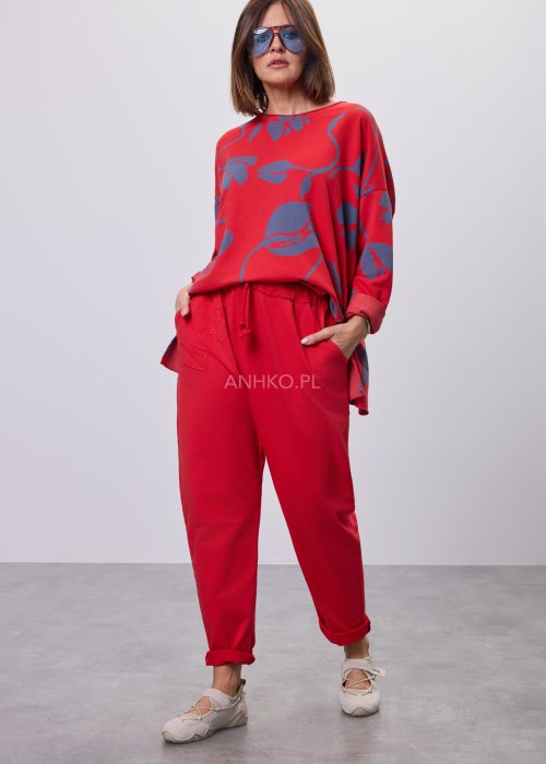 Czerwone spodnie damskie oversize z obniżonym krokiem i elastyczną talią, zestawione z jasną bluzką w casualowej stylizacji.