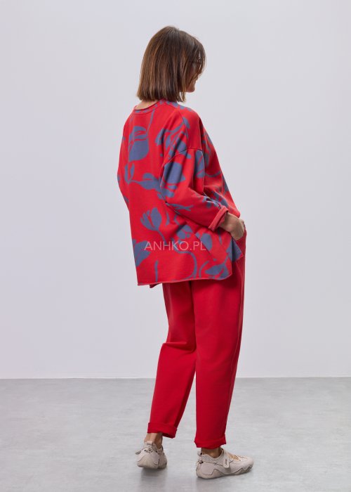 Czerwone spodnie damskie oversize z obniżonym krokiem i elastyczną talią, zestawione z jasną bluzką w casualowej stylizacji.