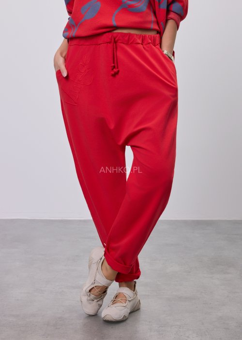 Czerwone spodnie damskie oversize z obniżonym krokiem i elastyczną talią, zestawione z jasną bluzką w casualowej stylizacji.