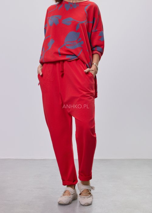 Czerwone spodnie damskie oversize z obniżonym krokiem i elastyczną talią, zestawione z jasną bluzką w casualowej stylizacji.