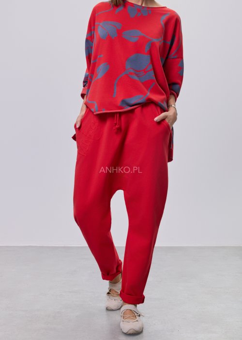 Czerwone spodnie damskie oversize z obniżonym krokiem i elastyczną talią, zestawione z jasną bluzką w casualowej stylizacji.