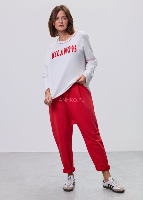 Czerwone spodnie damskie oversize z obniżonym krokiem i elastyczną talią, zestawione z jasną bluzką w casualowej stylizacji.