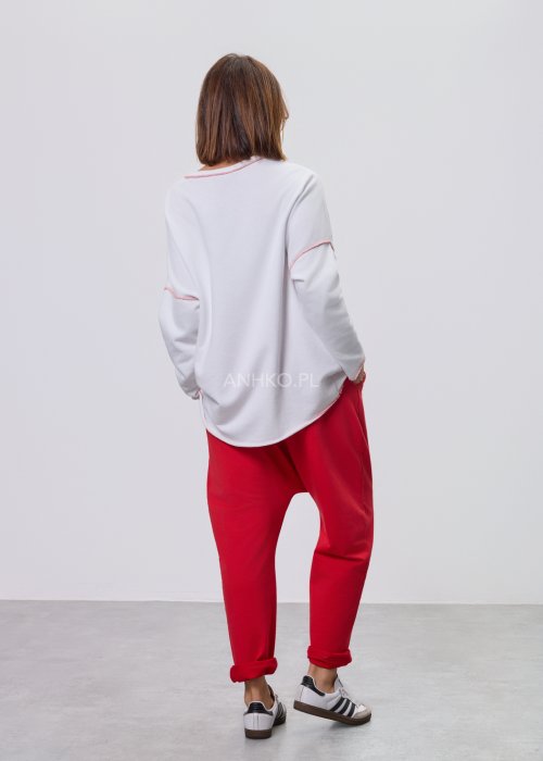Czerwone spodnie damskie oversize z obniżonym krokiem i elastyczną talią, zestawione z jasną bluzką w casualowej stylizacji.