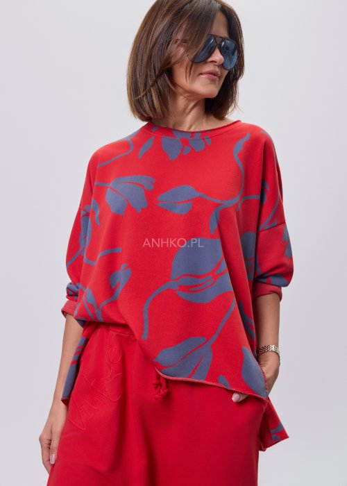 Czerwona damska bluzka o luźnym kroju, z długim rękawem i abstrakcyjnym granatowym nadrukiem, wykonana z miękkiej dzianiny