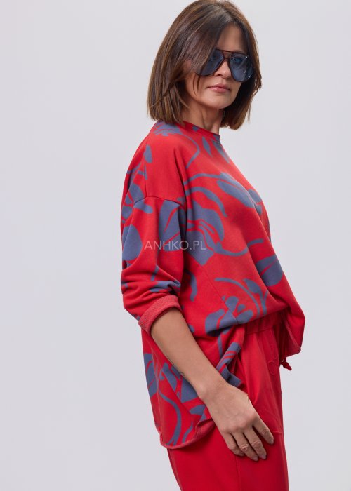 Czerwona damska bluzka o luźnym kroju, z długim rękawem i abstrakcyjnym granatowym nadrukiem, wykonana z miękkiej dzianiny