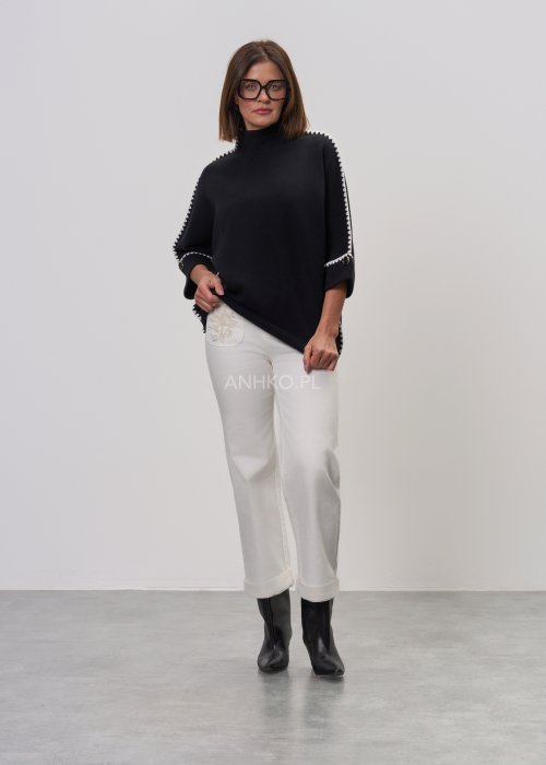 Czarna damska bluzka o luźnym kroju, z półgolfem i rękawami 3/4, ozdobiona kontrastową białą lamówką wzdłuż ramion i rękawów oraz dekoracyjnymi guzikami.