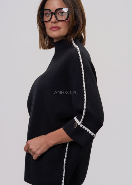 Czarna damska bluzka o luźnym kroju, z półgolfem i rękawami 3/4, ozdobiona kontrastową białą lamówką wzdłuż ramion i rękawów oraz dekoracyjnymi guzikami.