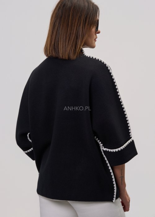 Czarna damska bluzka o luźnym kroju, z półgolfem i rękawami 3/4, ozdobiona kontrastową białą lamówką wzdłuż ramion i rękawów oraz dekoracyjnymi guzikami.