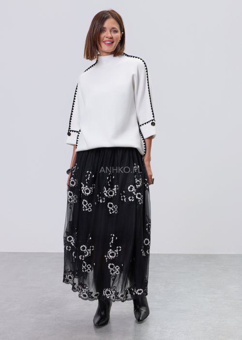 Biała damska bluzka o luźnym kroju z półgolfem i rękawami 3/4, wykończona kontrastową czarną lamówką wzdłuż ramion, rękawów i boków oraz ozdobnymi guzikami przy mankietach