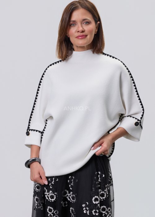 Biała damska bluzka o luźnym kroju z półgolfem i rękawami 3/4, wykończona kontrastową czarną lamówką wzdłuż ramion, rękawów i boków oraz ozdobnymi guzikami przy mankietach