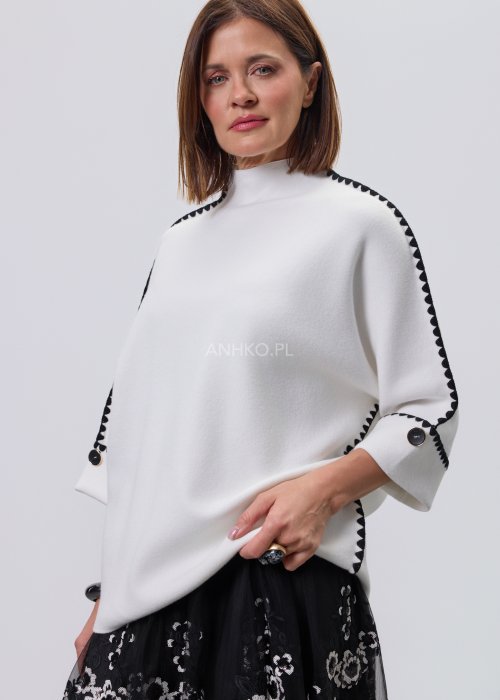 Biała damska bluzka o luźnym kroju z półgolfem i rękawami 3/4, wykończona kontrastową czarną lamówką wzdłuż ramion, rękawów i boków oraz ozdobnymi guzikami przy mankietach