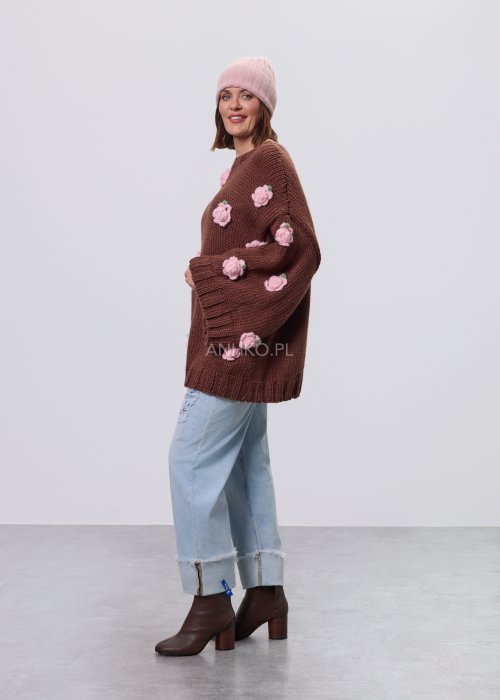 Brązowa damska bluzka–sweter o luźnym kroju, wykonana z grubej dzianiny, ozdobiona aplikacjami w formie różowych kwiatów, z długimi rękawami i okrągłym dekoltem