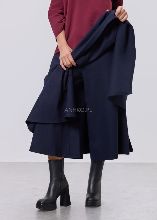 Granatowe damskie spódnico-spodnie o długości midi, z szerokimi, warstwowymi nogawkami imitującymi spódnicę, wykonane z gładkiej tkaniny