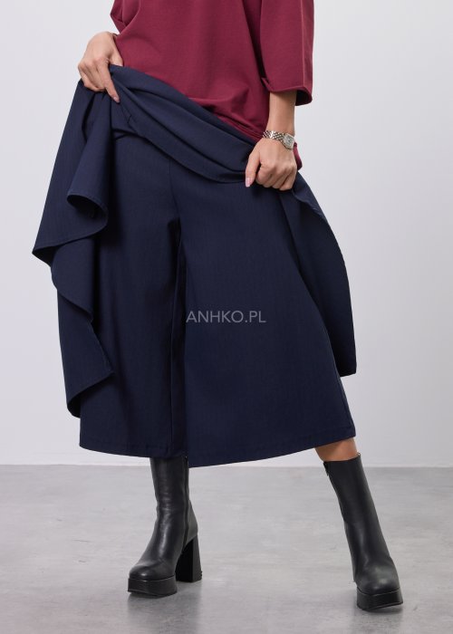 Granatowe damskie spódnico-spodnie o długości midi, z szerokimi, warstwowymi nogawkami imitującymi spódnicę, wykonane z gładkiej tkaniny