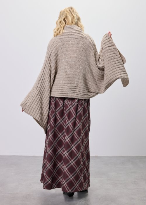 Beżowy damski kardigan o luźnym, oversize’owym kroju z grubego, prążkowanego splotu, noszony nonszalancko na ramionach